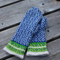 Pair of blue and green patterned mittens on a wooden surface