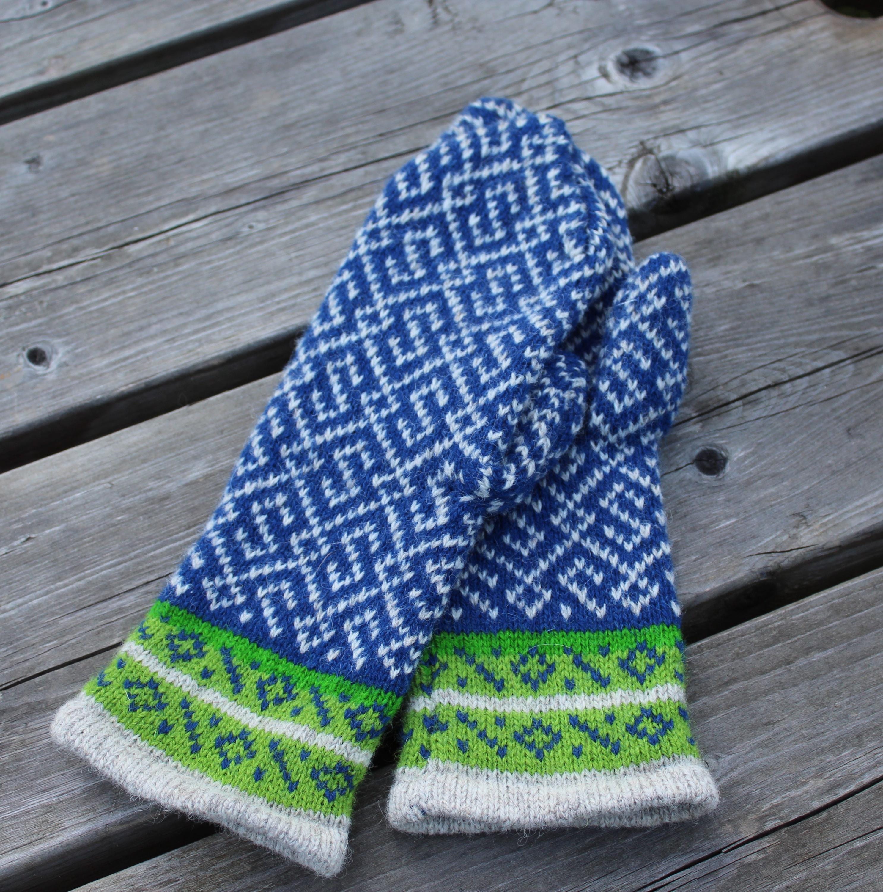 Pair of blue and green patterned mittens on a wooden surface