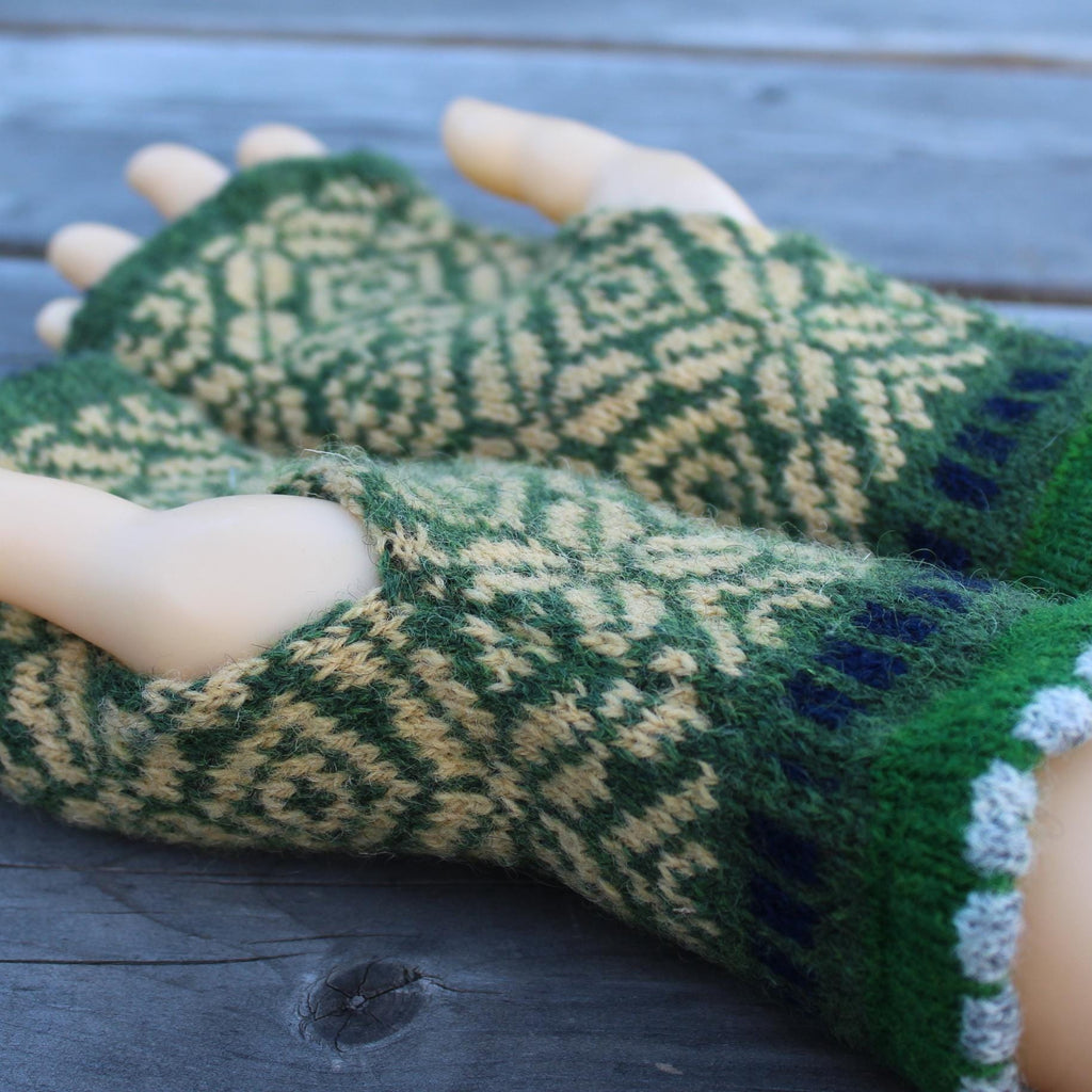 Green and yellow wool hand warmers  on a wooden surface