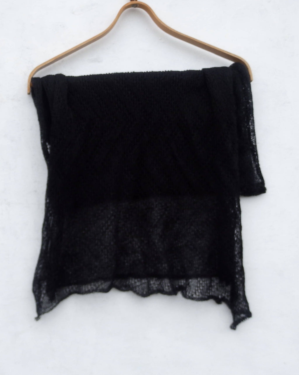 Black scarf on a wooden hanger against a white background