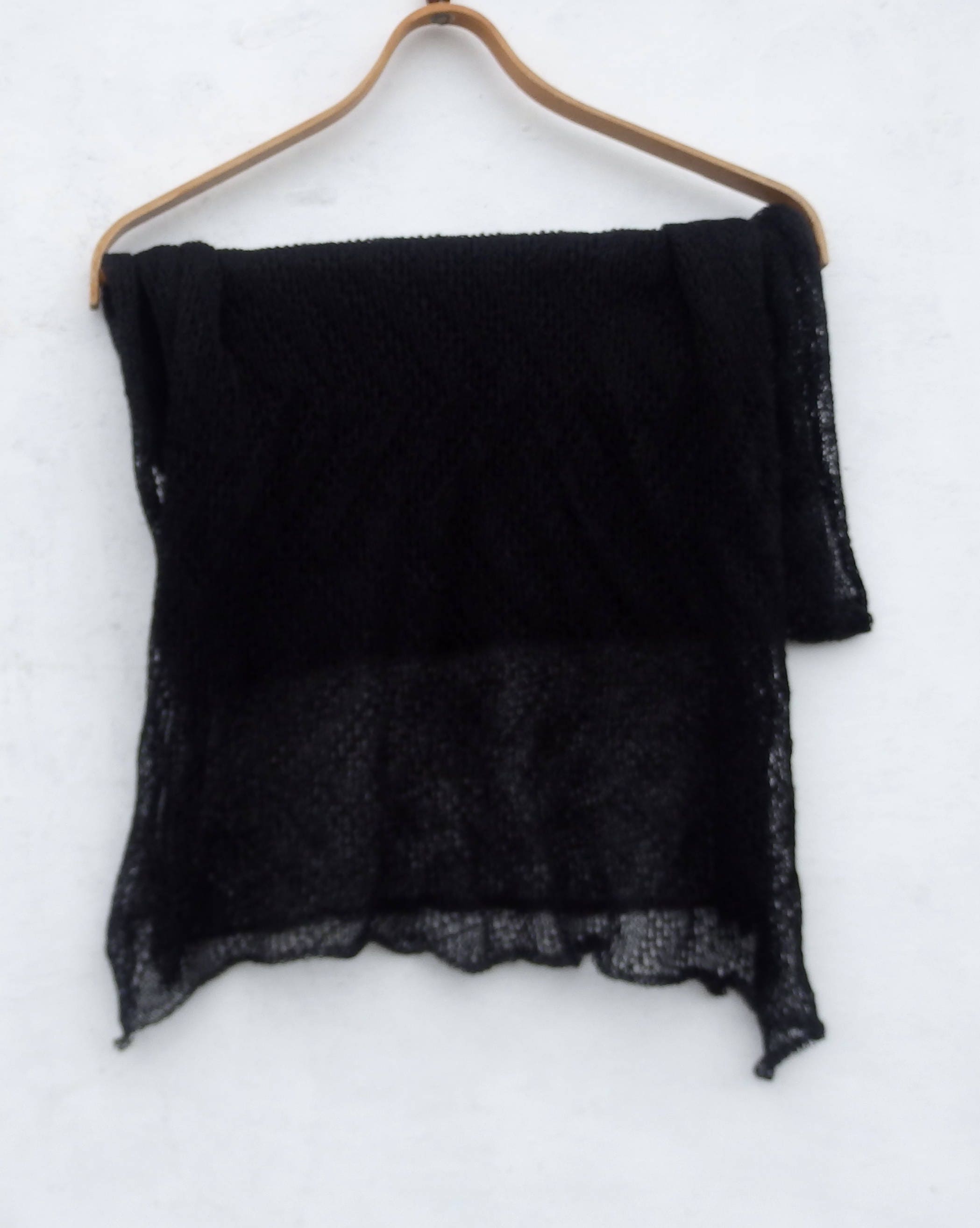 Black scarf on a wooden hanger against a white background