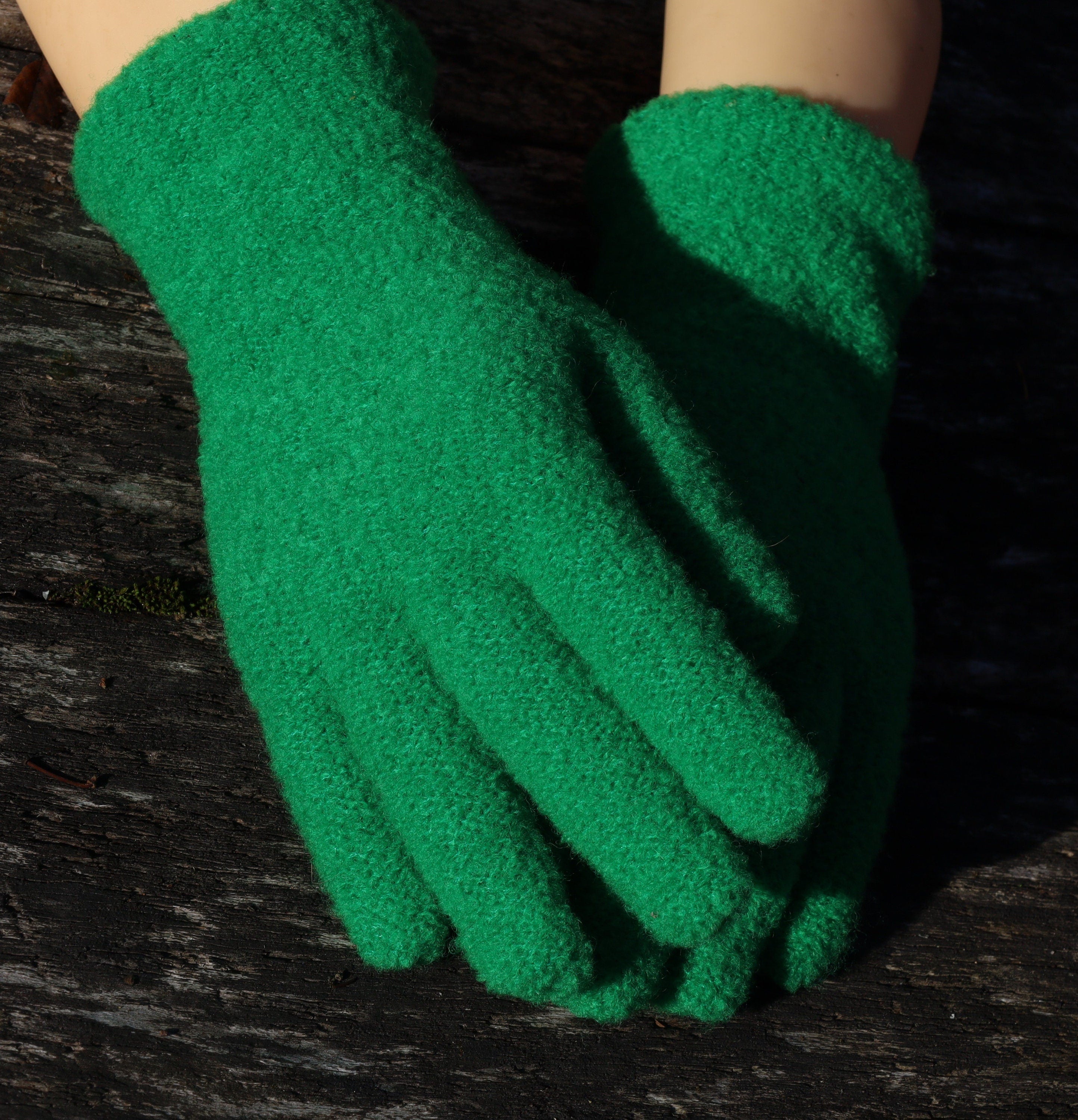 Green gardening gloves on a dark wooden surface