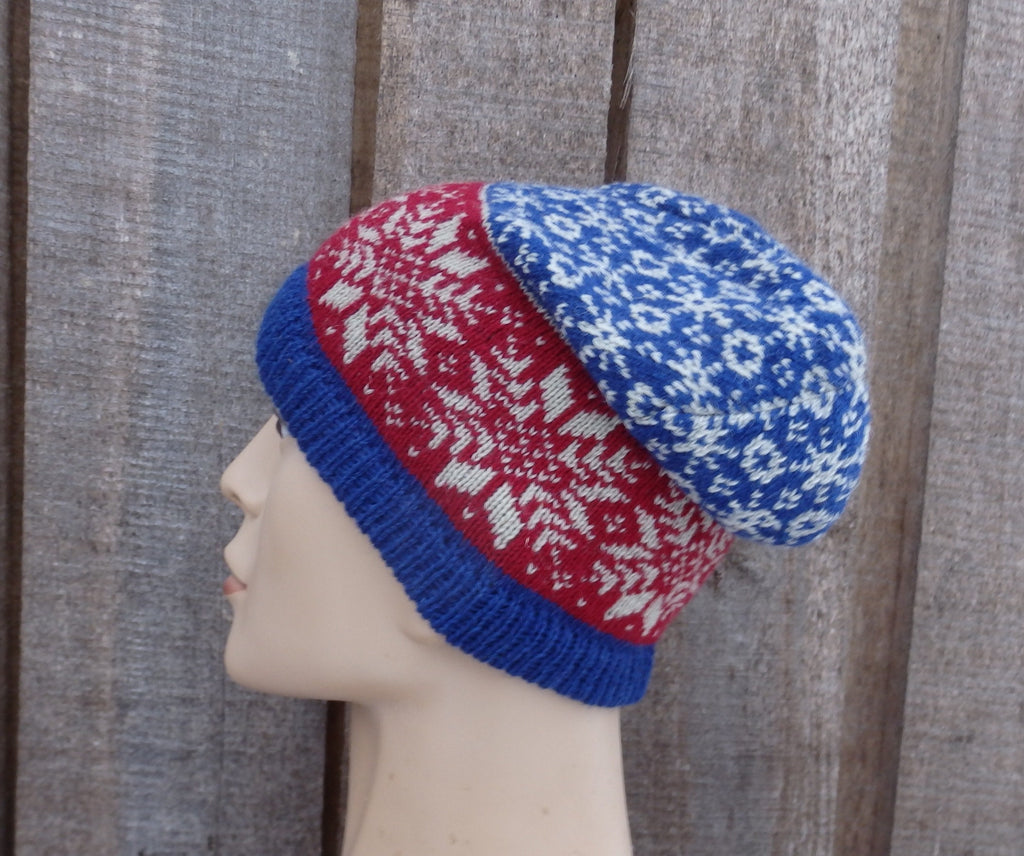 Knitted hat with red and blue pattern on a mannequin head against a wooden background