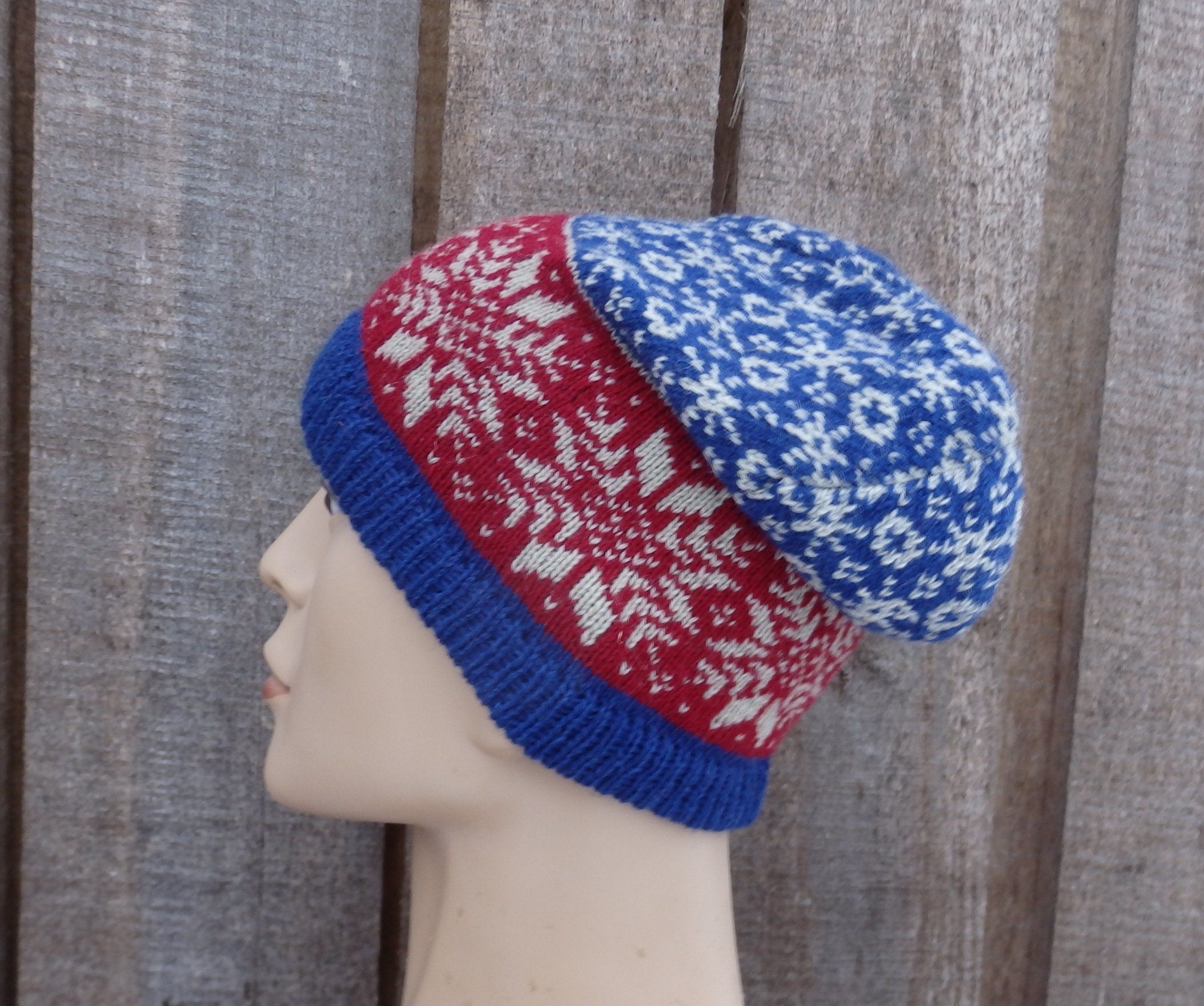 Knitted hat with red and blue pattern on a mannequin head against a wooden background