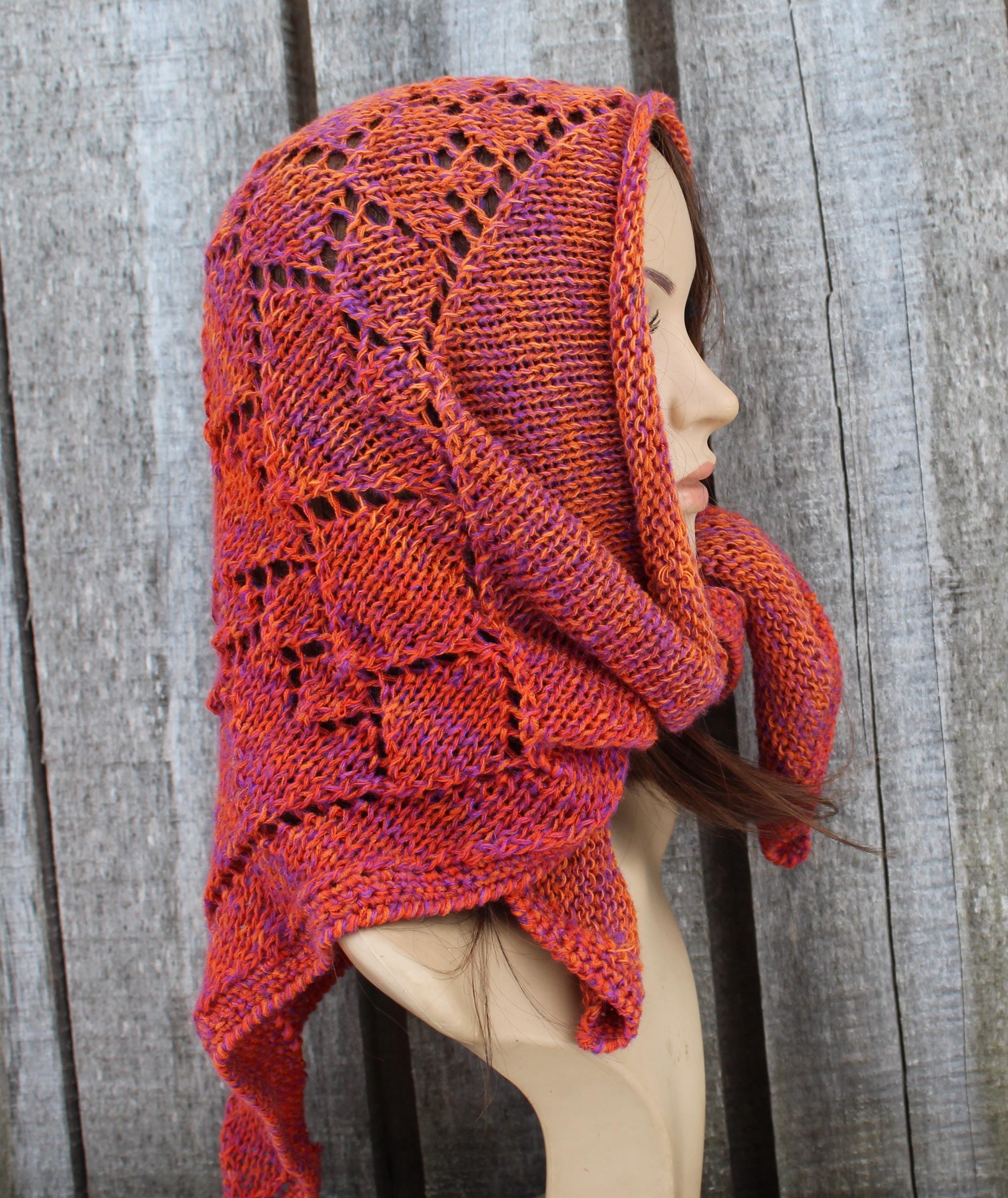 Knitted kerchief in orange on a mannequin against a wooden background
