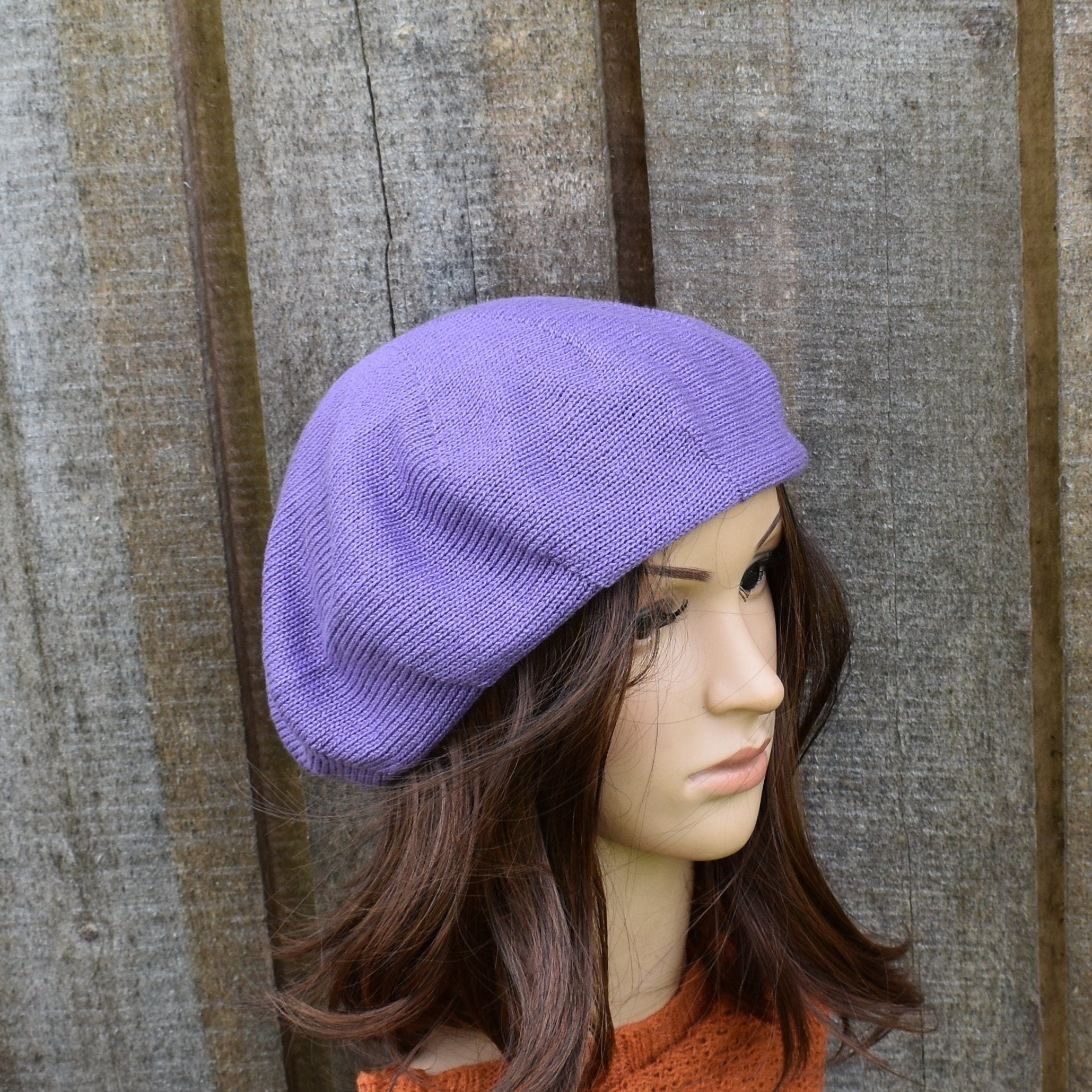 Purple beret on a mannequin head against a wooden background
