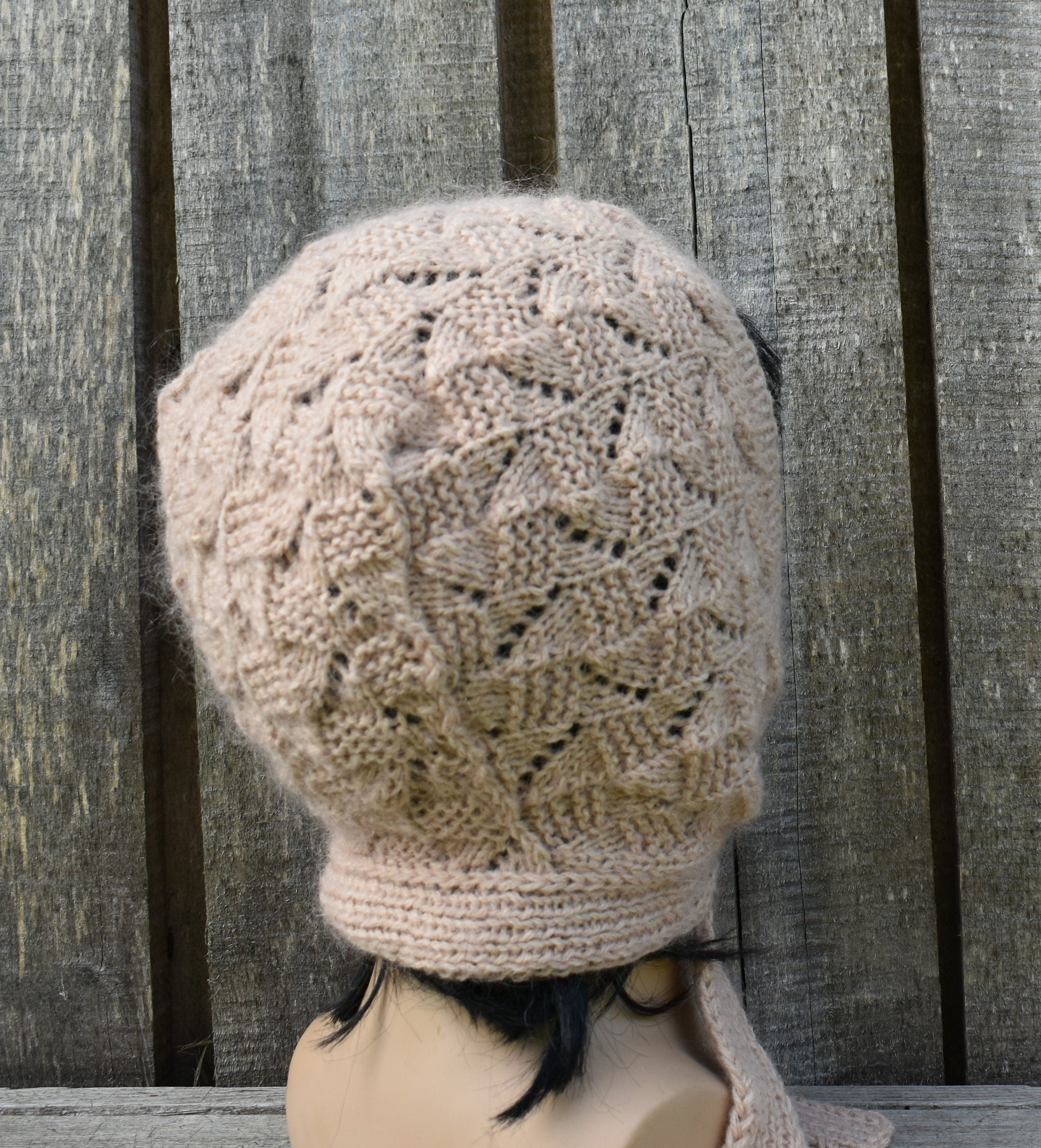 Knitted beige beanie on a mannequin head against a wooden background