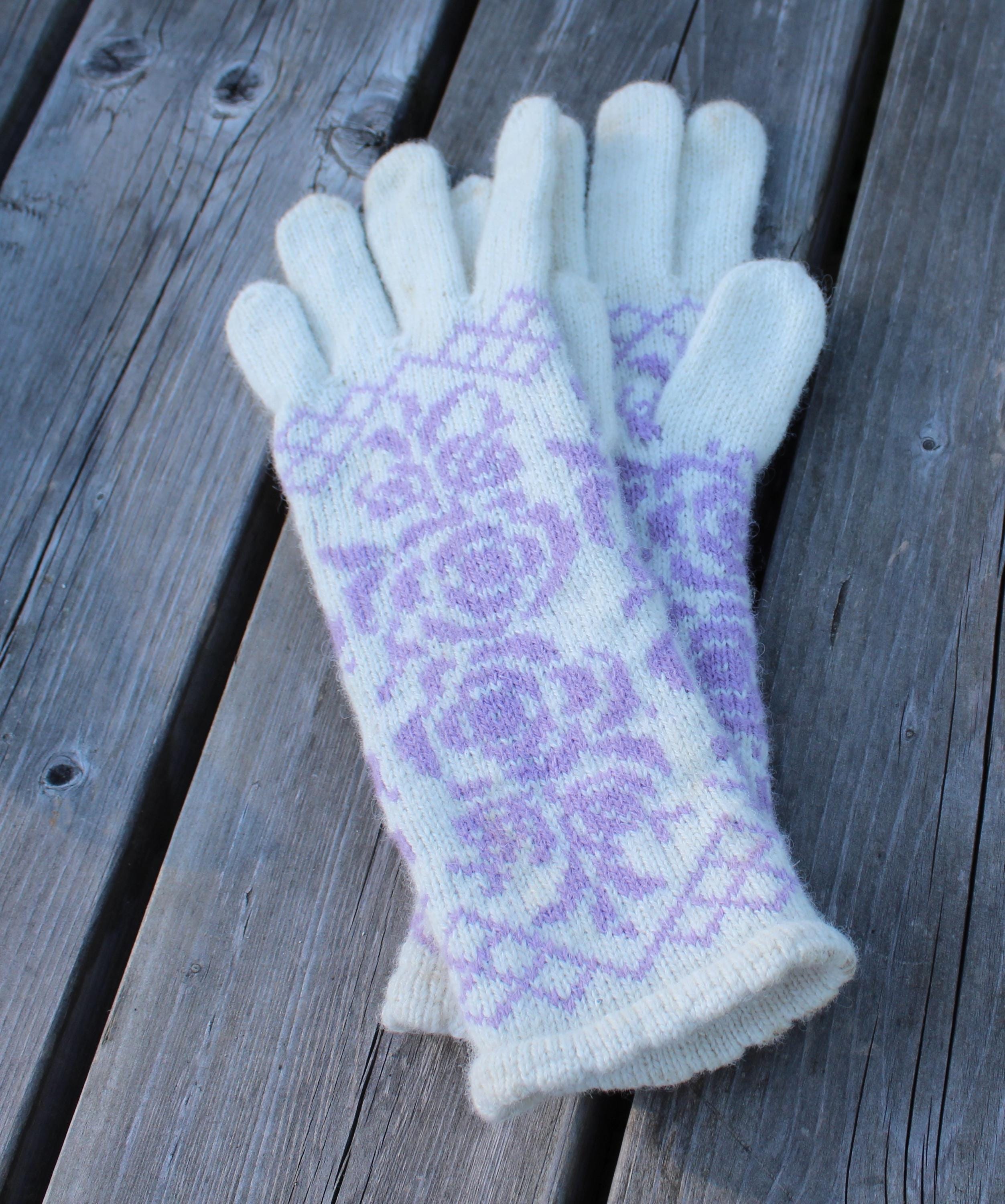 Pair of cream gloves with purple floral pattern on a wooden surface