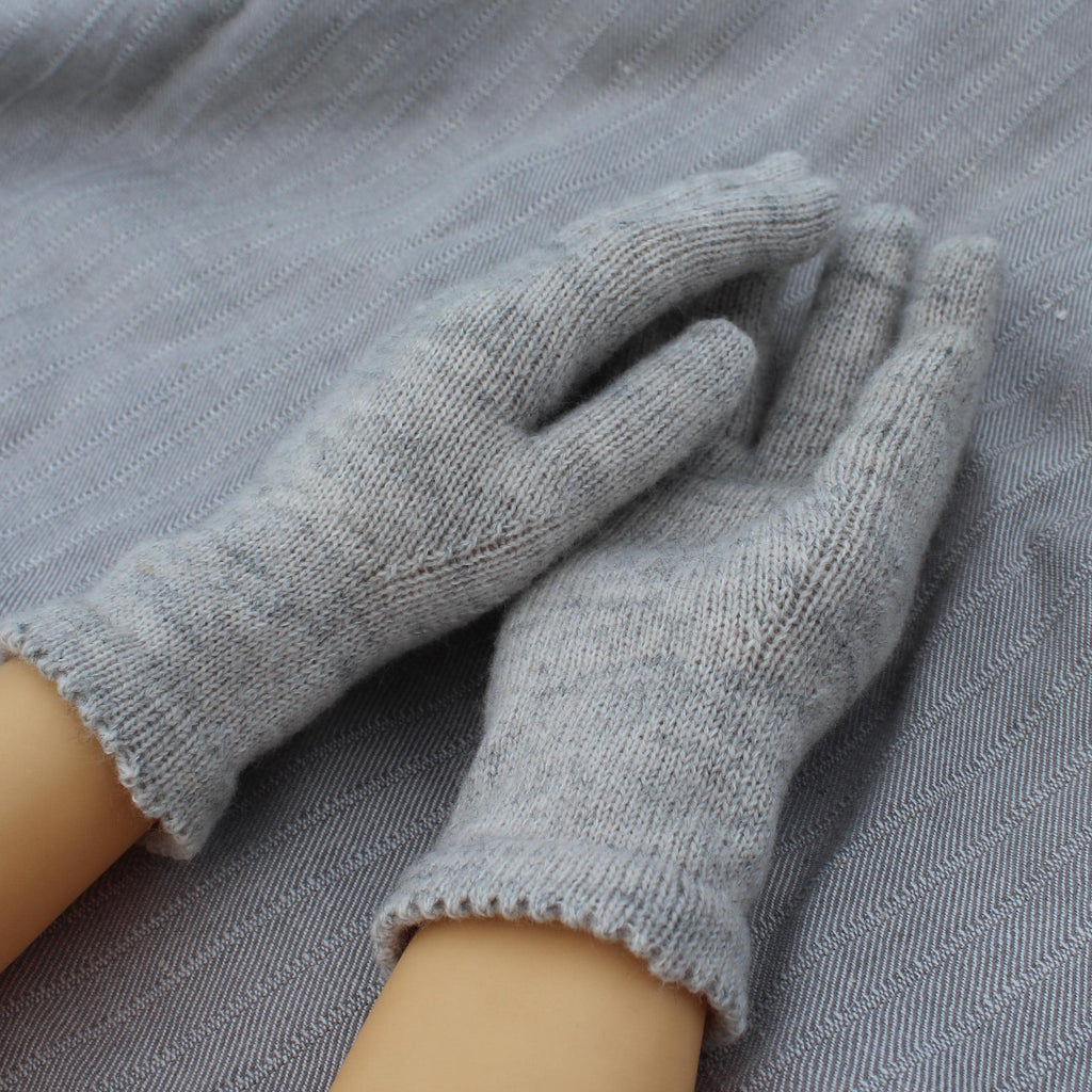 Gray gloves being worn on a gray fabric background