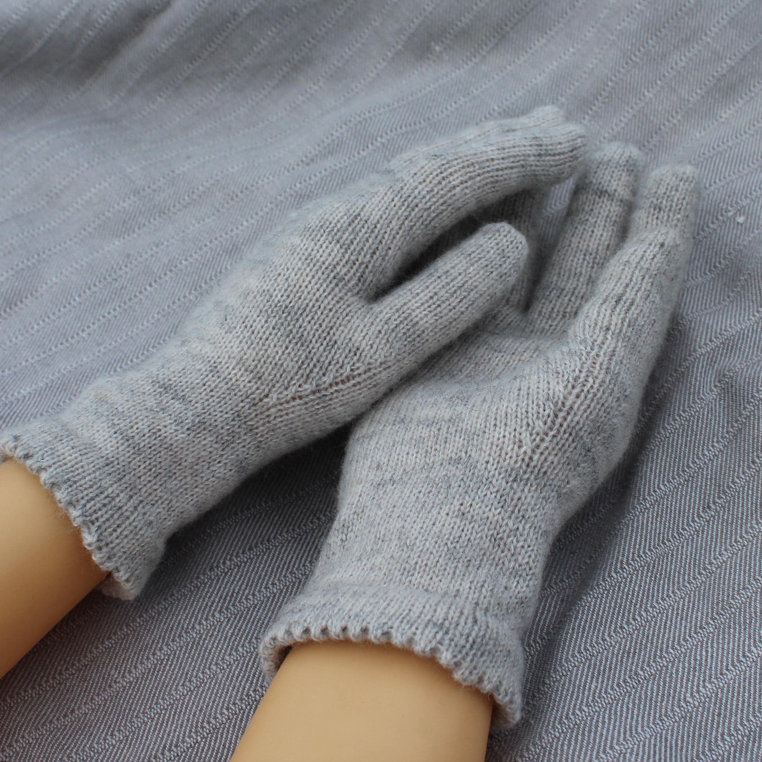 Gray gloves being worn on a gray fabric background