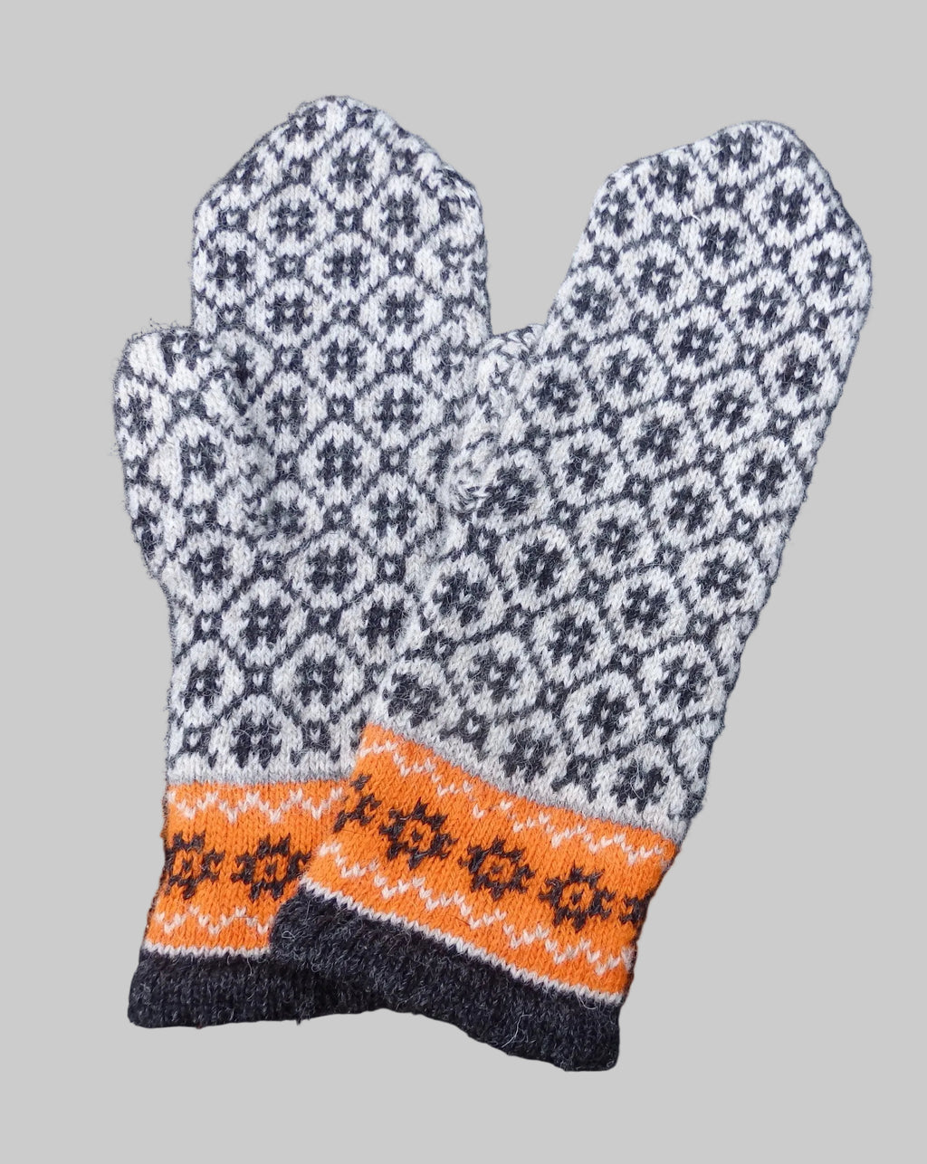Pair of knitted mittens with a geometric pattern on a dark background