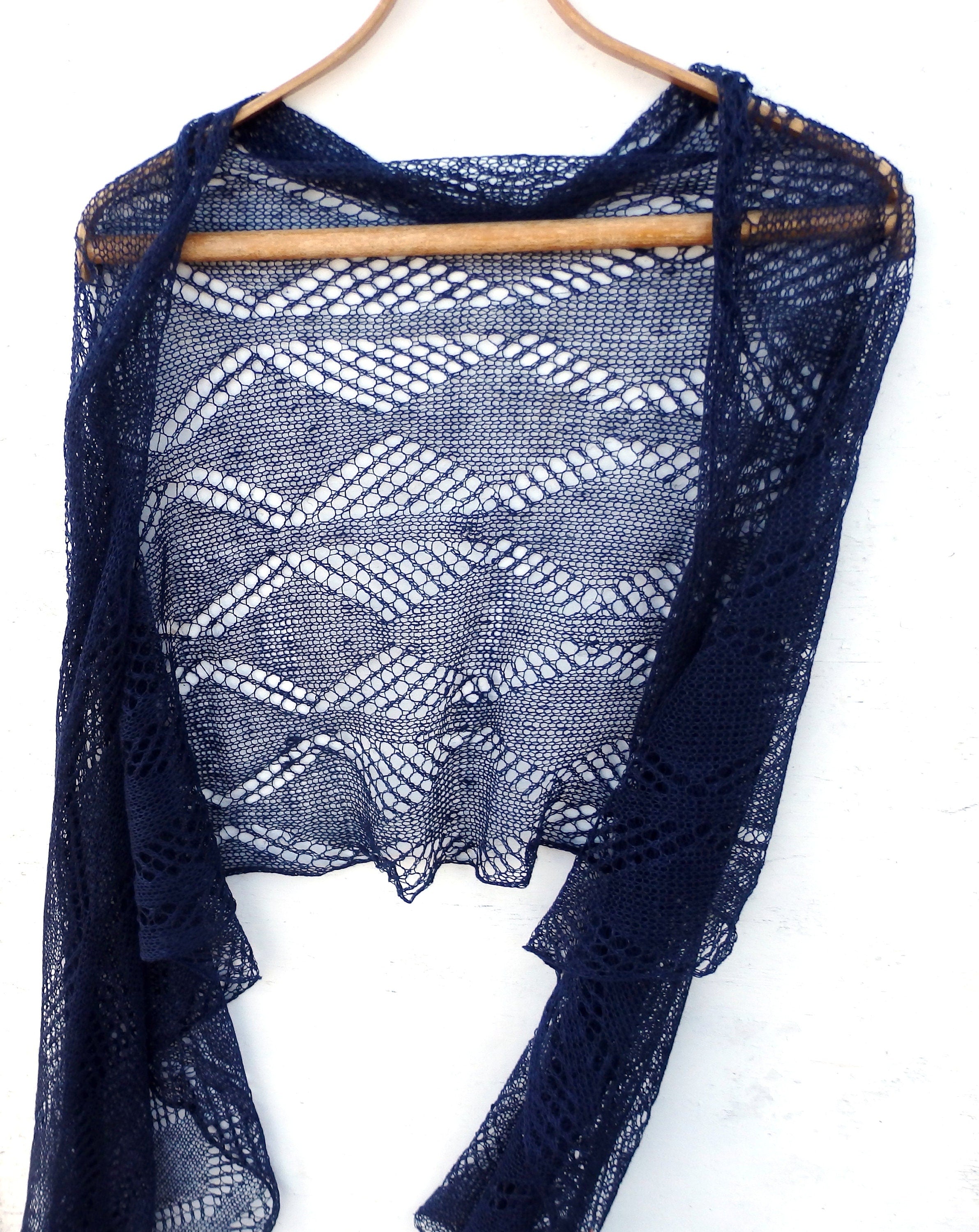 Navy blue lace shawl on a wooden hanger against a white background