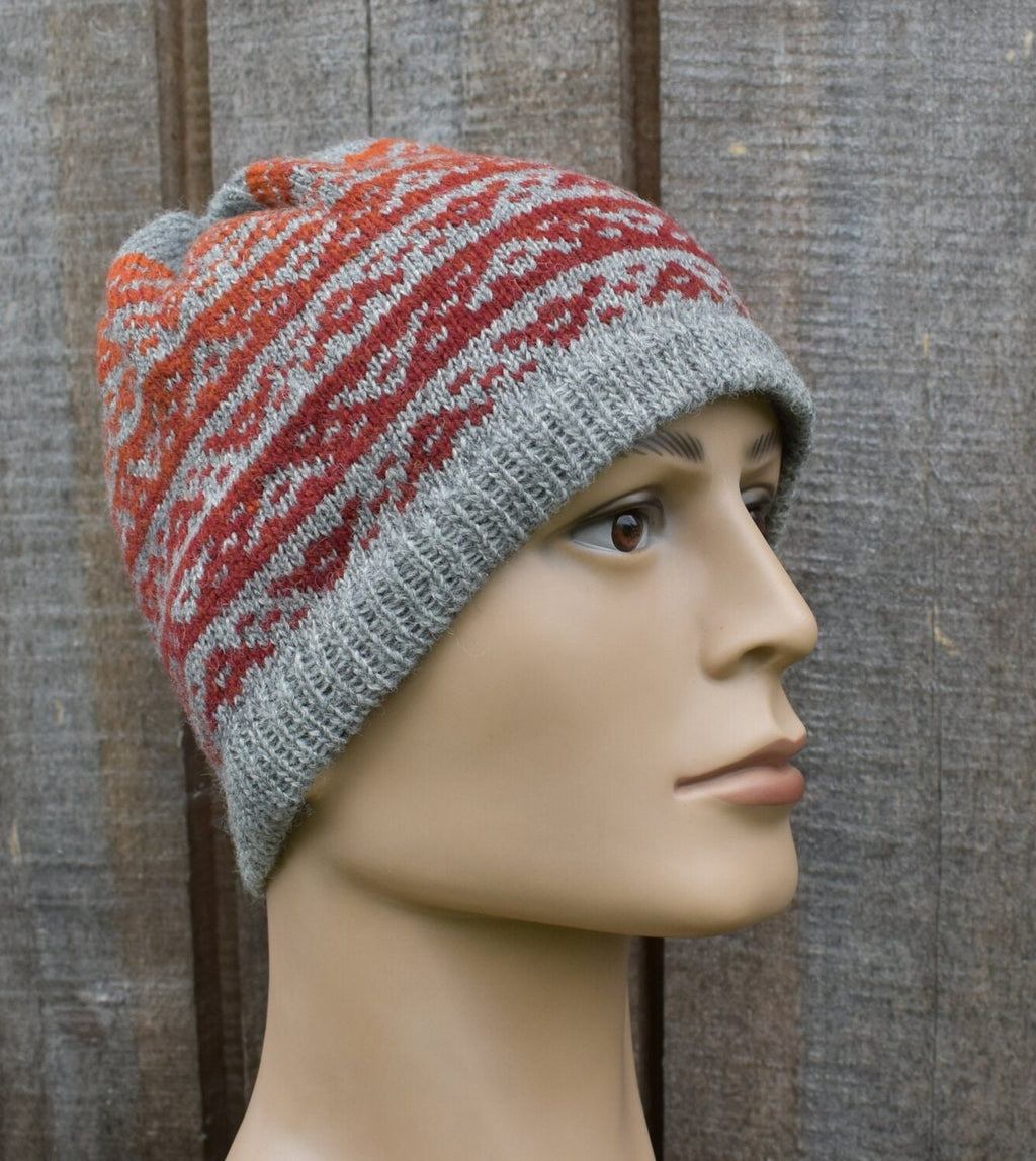 Knitted hat with red and gray pattern on a mannequin head against a wooden background