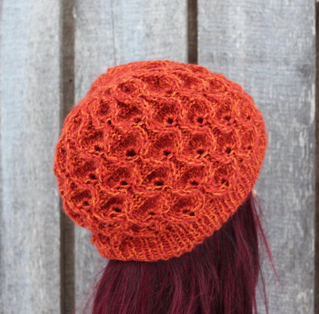 Orange knitted hat on a mannequin head against a wooden background