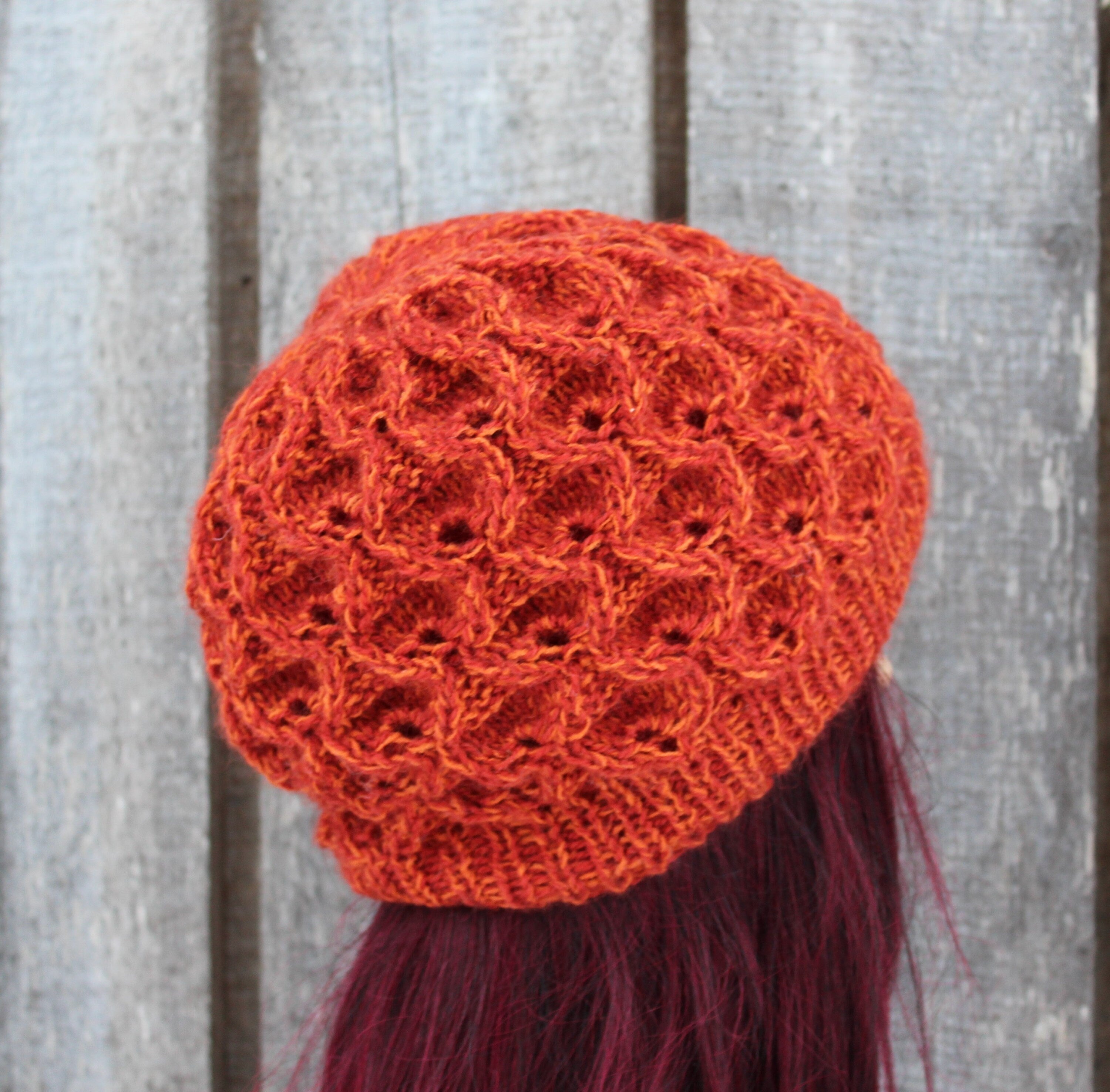 Orange knitted hat on a mannequin head against a wooden background